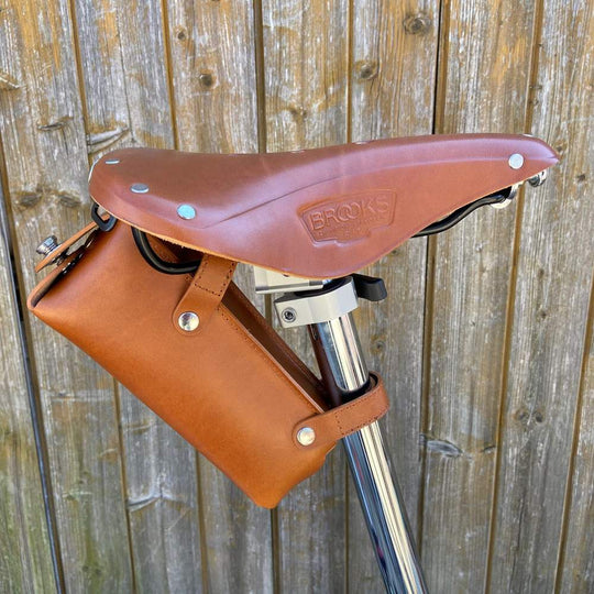 Honey bicycle saddle bag large with black hardware against a wooden background side view