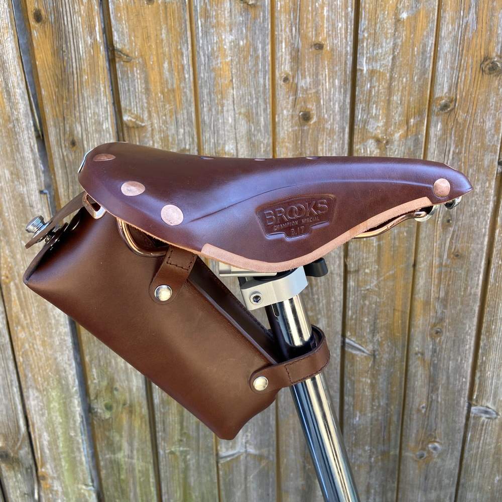 Brown bicycle saddle bag large with silver hardware against a wooden background