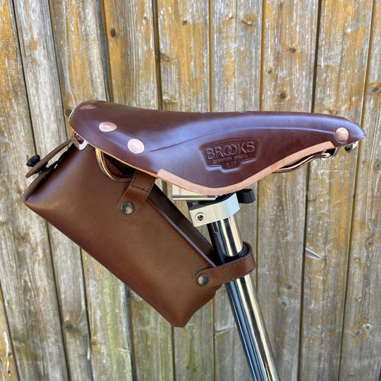 Brown leather bicycle saddle bag side view against a wooden background