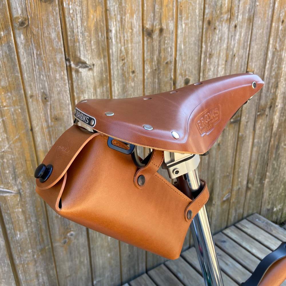 honey bicycle saddle bag large with black hardware against a wooden background