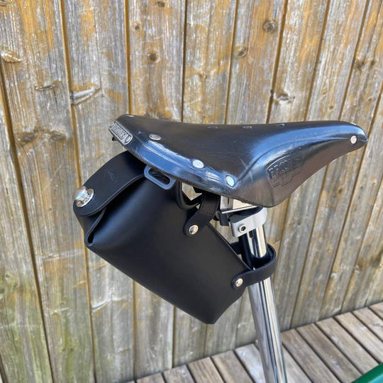 Black bicycle saddle bag large with silver hardware against a wooden background