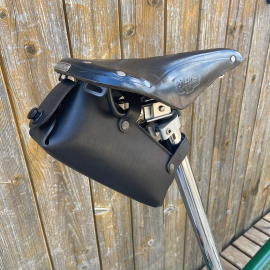 Black bicycle saddle bag large with black hardware against a wooden background