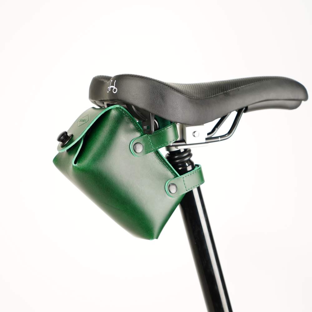 Green bicycle saddle bag with black hardware sideview on white background