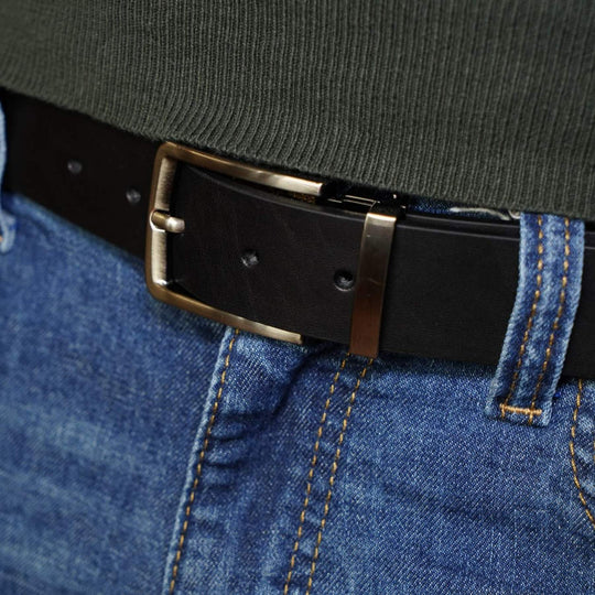 Close-up of a black belt with a brass buckle on blue jeans.
