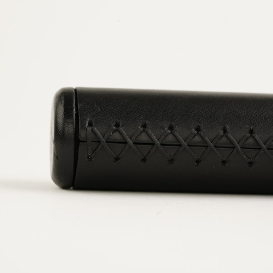 Black leather handlebar grip with woven pattern on a white background