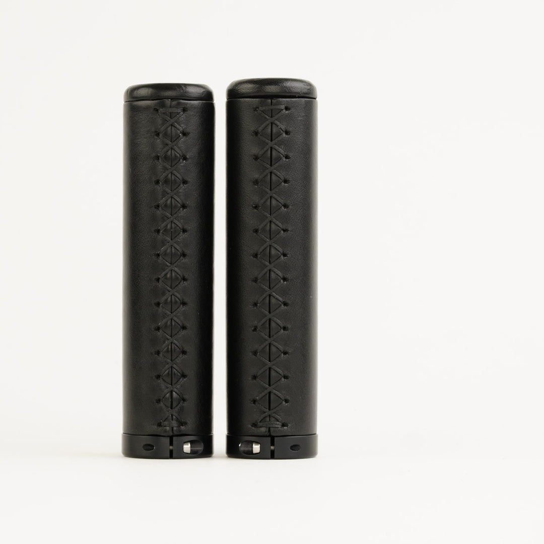 Pair of black bicycle grips with stitching on white background